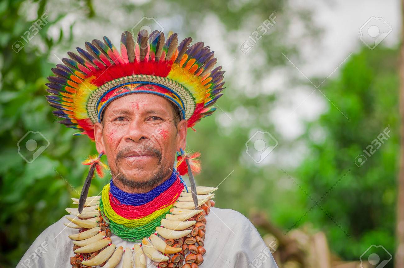 LAGO AGRIO, ECUADOR - NOVEMBER 17, 2016: Close up of a Siona shaman in traditional dress with a feather hat in an indigenous village in the Cuyabeno Wildlife Reserve